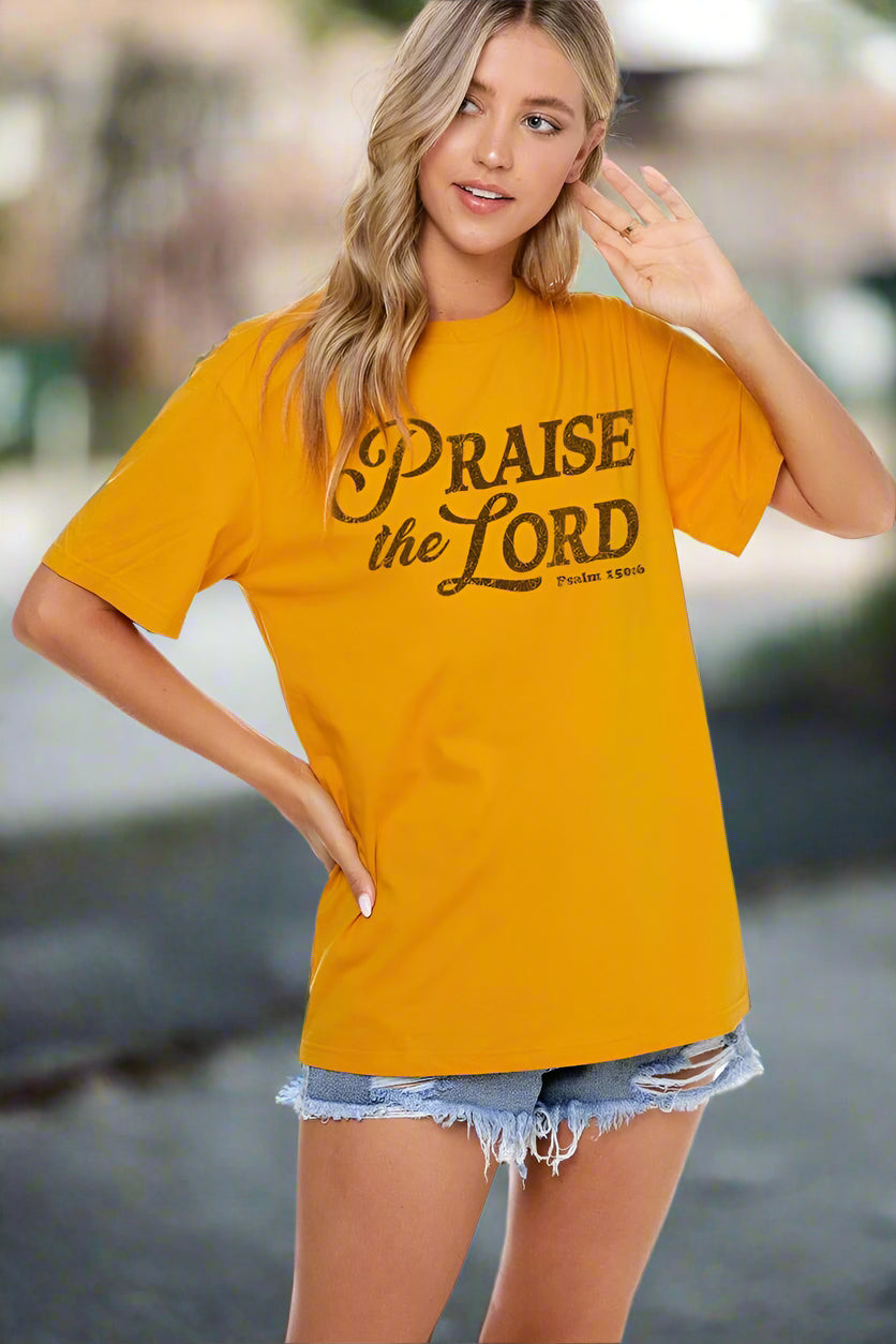 Woman wearing a yellow t-shirt with 'Praise the Lord' text on a white background